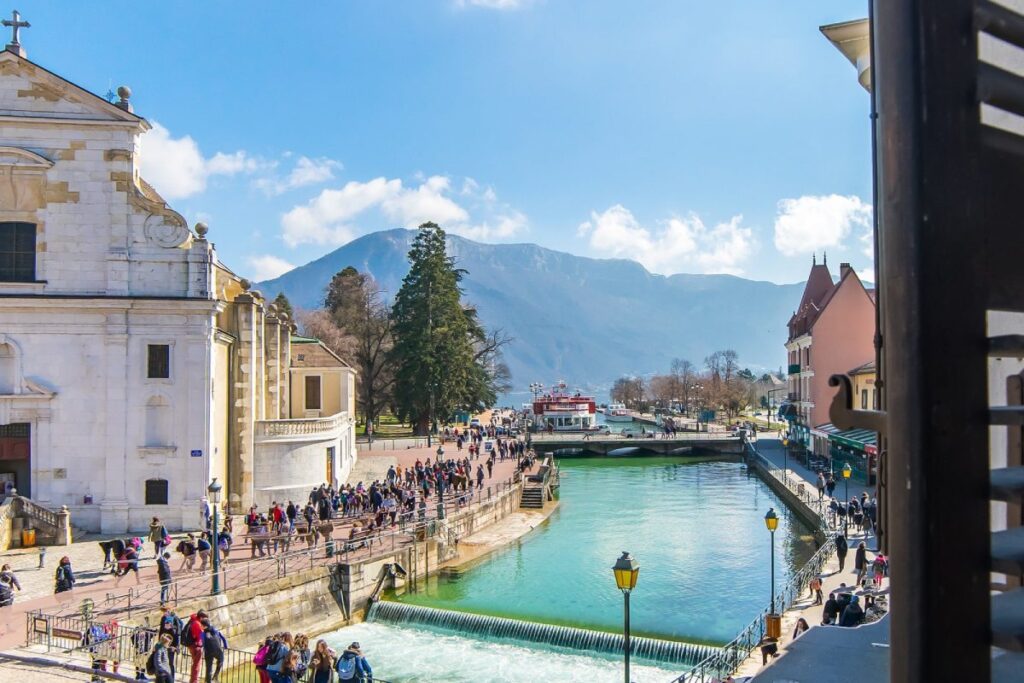 Vista del canale del Thiou ad Annecy con il Palais de lIsle, passanti e montagne sullo sfondo